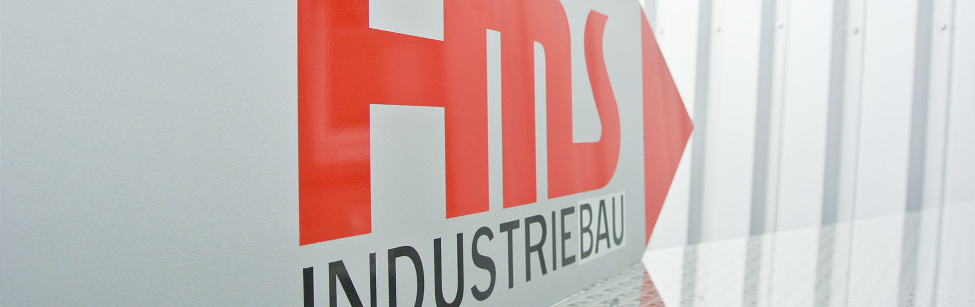 Logo der HMS Industriebau in der Perspektive auf einem Baustellenschild