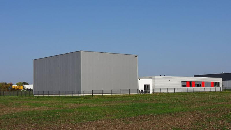 Aus dem Himmel ragt eine hohe Präsentationshalle für Maschinen der Trimill GmbH.  Die Deckenhöhe von fast 10 Metern zeigt sich bis weit über die Grenzen von Herford und OWL hinaus.